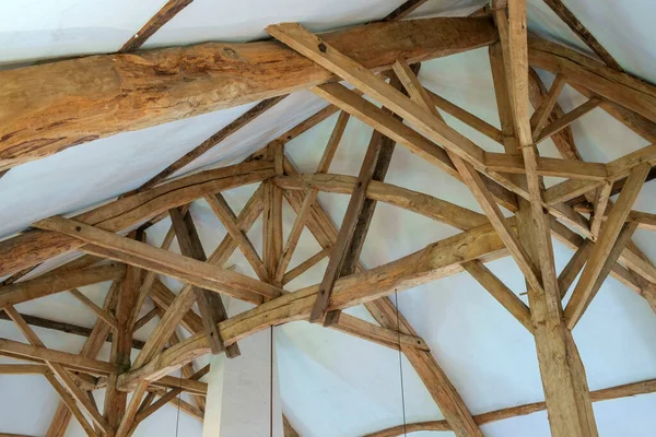 Looking up at the massive restored interior timber roof construction in a large  old French farmhouse