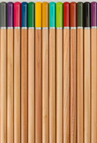 Artists watercolour pencils on a textured white paper surface, the wood and coloured pencil end make a pattern