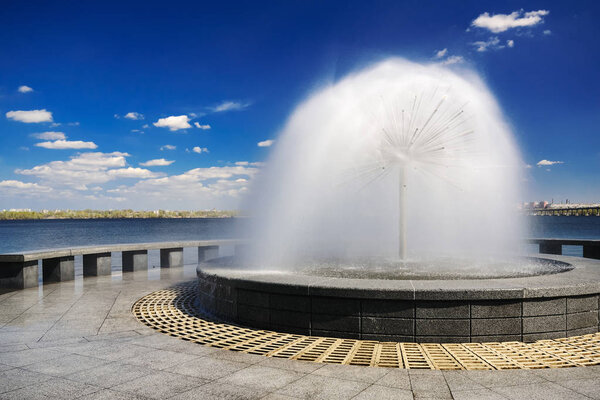 Beautiful fountain against the blue sky with clouds XI