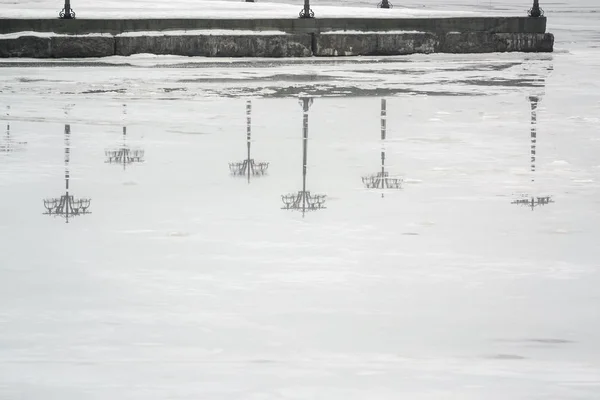 Відображення набережної з ліхтарями на льоду взимку в річці раннього туманного ранку — стокове фото
