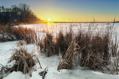 Donmuş göl ve günbatımı gökyüzü ile güzel kış manzarası.