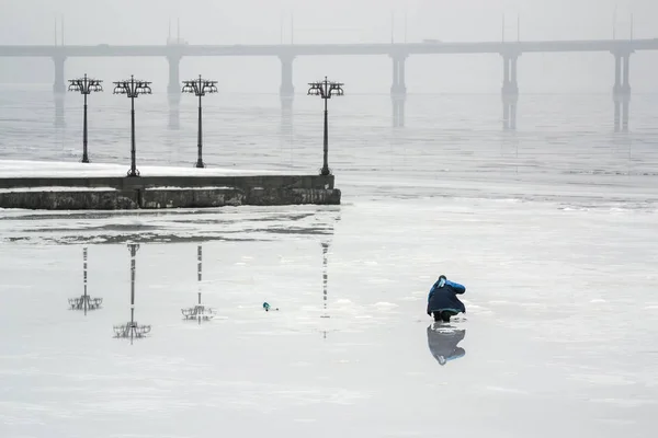 A halász halászat a jég a befagyott folyón egy korai Ködös reggel — Stock Fotó