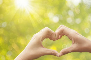 Eller şekil doğa yeşil bokeh güneş ışık parlama üzerinde kalp ve yaprak arka plan bulanıklık. 