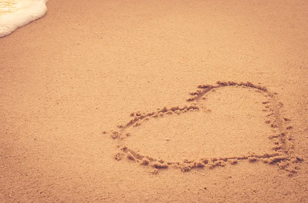 Corazón dibujo en la playa de arena con ola suave . —  Fotos de Stock