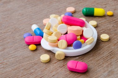 Ahşap arka plan üzerinde renkli ilaç kapsül pill kapatın.
