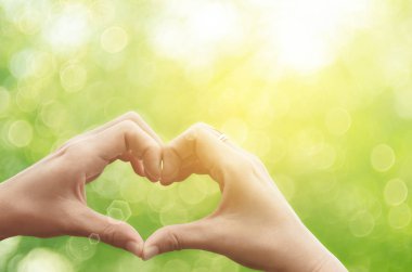 Eller şekil doğa yeşil bokeh güneş ışık parlama üzerinde kalp ve yaprak arka plan bulanıklık.