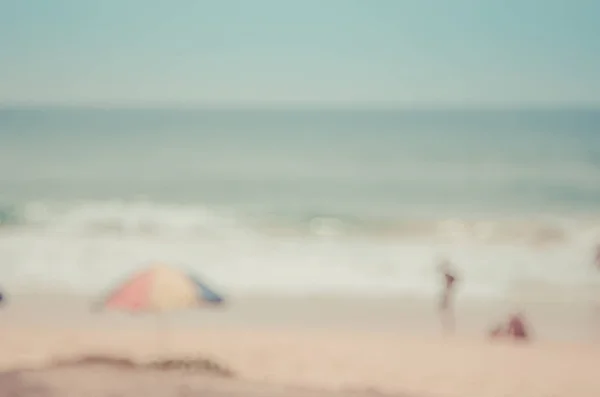 Le persone sfocate rilassarsi sulla spiaggia tropicale e ombrello spiaggia sfondo astratto. Concetto di viaggio . — Foto Stock