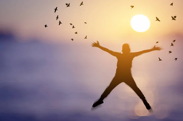 Freiheit und Wohlfühlkonzept. Kopie Raum der Silhouette glücklicher Mann springen auf verschwommenen tropischen Sonnenuntergang Strand mit Vögeln fliegen abstrakten Hintergrund. — Stockfoto