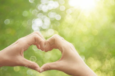 Eller şekil doğa yeşil bokeh güneş ışık parlama üzerinde kalp ve yaprak arka plan bulanıklık. 