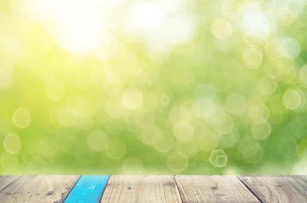 Verwischen grüne Natur Bokeh mit Sonnenlicht auf Kopierraum leer alten Holztisch abstrakten Hintergrund. — Stockfoto