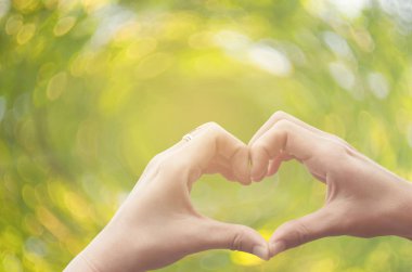 Eller şekil doğa yeşil bokeh güneş ışık parlama üzerinde kalp ve yaprak arka plan bulanıklık.