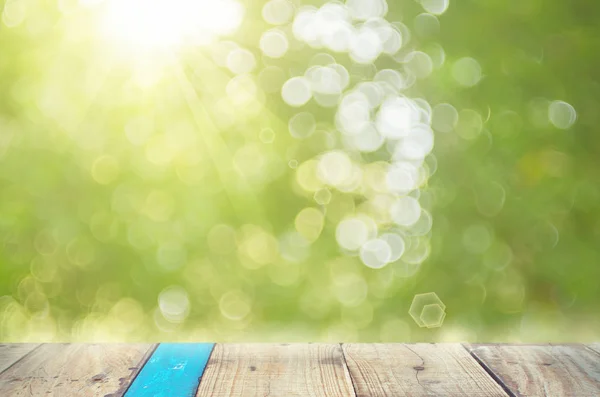 Verwischen grüne Natur Bokeh mit Sonnenlicht auf Kopierraum leer alten Holztisch abstrakten Hintergrund. — Stockfoto