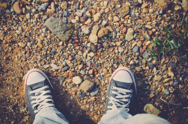 Küçük rock kum renkli arka plan, selfie ile zeminde Ayakkabı ve mavi jean Üstten Görünüm. 