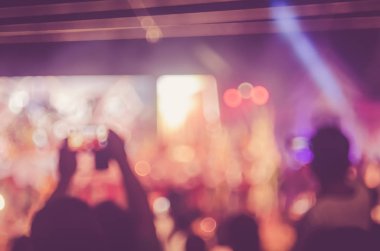 Gece açık konserinde renkli bokeh arka plan ile akıllı telefon alan insanlar bulanıklık.