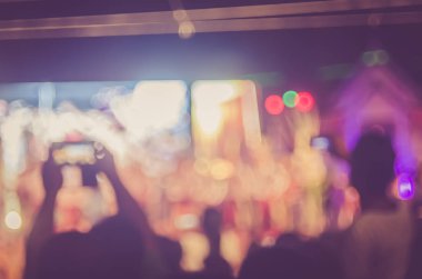 Gece açık konserinde renkli bokeh arka plan ile akıllı telefon alan insanlar bulanıklık.