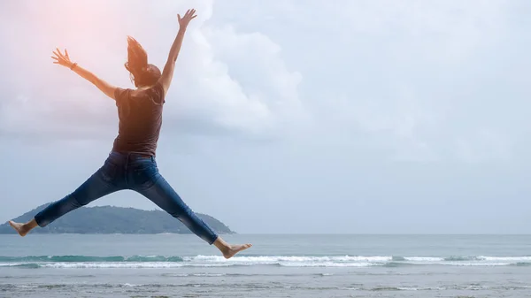 Wohlfühl- und Freiheitskonzept. Kopierraum einer glücklichen Frau, die am Strand springt. — Stockfoto
