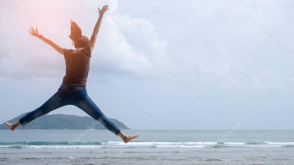 Feel good and freedom concept. Copy space of happy woman jumping on beach. 