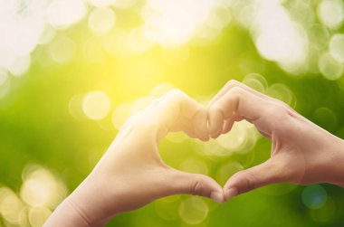 Eller şekil doğa yeşil bokeh güneş ışık parlama üzerinde kalp ve yaprak arka plan bulanıklık. 