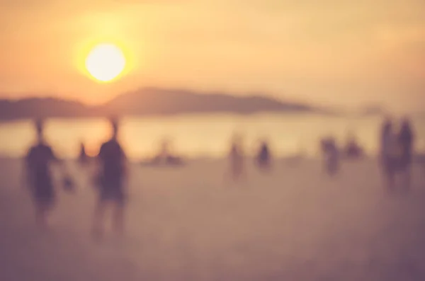 Θαμπάδα ανθρώπους να χαλαρώσουν σε τροπική παραλία ηλιοβασίλεμα αφηρημένα φόντο. — Φωτογραφία Αρχείου
