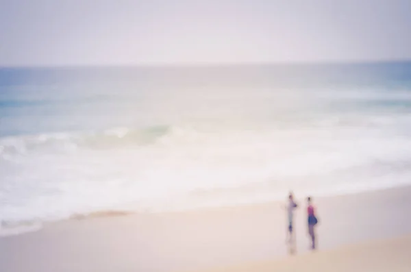 Vervagen mensen ontspannen op tropische zonsondergang strand met bokeh zon lichtgolf abstracte achtergrond. — Stockfoto