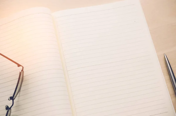 Kopie ruimte van nota boek met pen en glazen op de houten tafel achtergrond. — Stockfoto