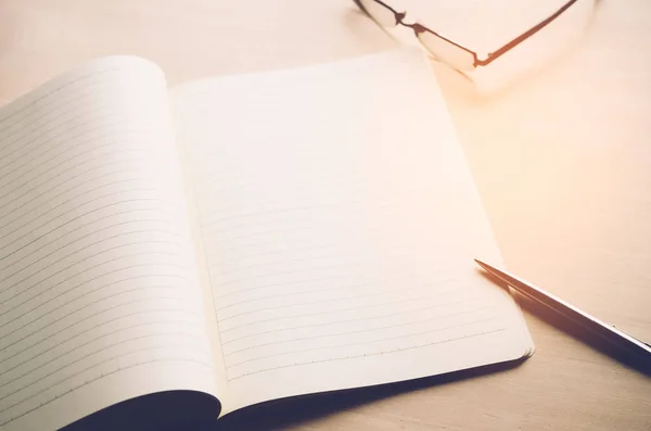 Kopie ruimte van nota boek met pen en glazen op de houten tafel achtergrond. — Stockfoto