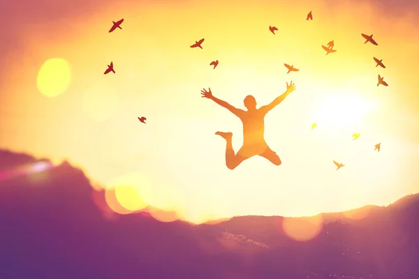 Silhouette Mann springen und Vögel fliegen auf Sonnenuntergang Himmel und Wolke Textur abstrakten Hintergrund. — Stockfoto