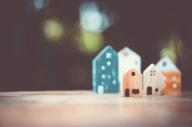 Ahşap masa üzerinde yeşil Bokeh soyut arka planına sahip küçük evler modeli. Aile hayatı ve iş yeri konsepti.