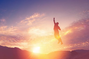 Mutlu adam, günbatımı gökyüzü arka plan ile dağın tepesine atlama.