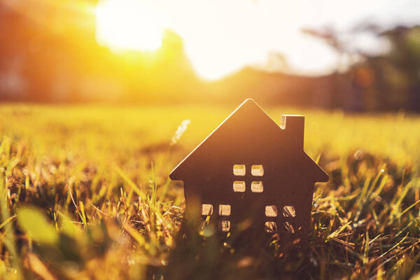 Копирование пространства дома и жизненной концепции. Маленький образцовый дом на зеленой траве на фоне солнечного света
.