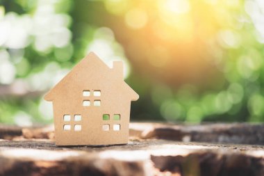 Ahşap masadaki küçük ev modeli, doğa yeşil bokeh soyut arka plan. Aile hayatı ve iş yeri konsepti.