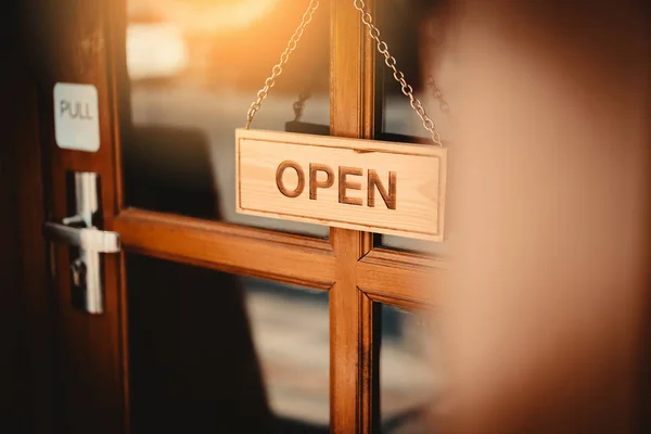 Cartel abierto amplio colgando en la puerta de madera frente a la cafetería . — Foto de Stock