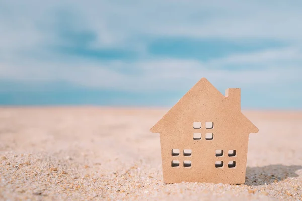 Mały model domu na zachodzie słońca Plaża piasku tekstury tła. — Zdjęcie stockowe
