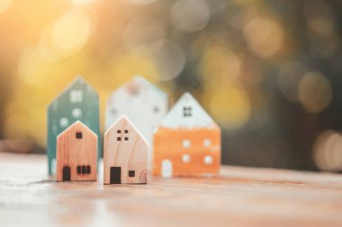 Ahşap masadaki küçük ev modeli, doğa yeşil bokeh soyut arka plan. Aile hayatı ve iş yeri konsepti.