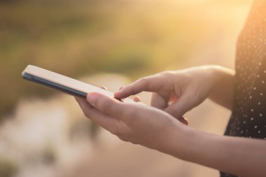 Kadın el yakından tutun park açık sokak arka plan üzerinde akıllı telefon kullanma.