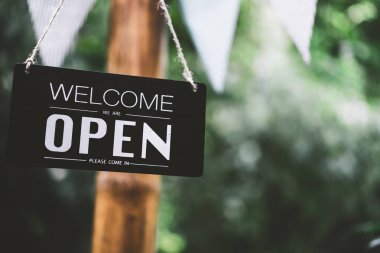 Açık işareti yeşil doğa bokeh güneş ışığı arka plan ile ağaç asılı.