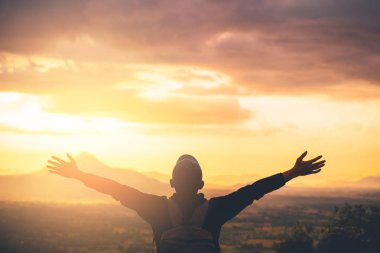 Backpacker adam altında el kadar günbatımı gökyüzü ile dağın zirvesinde yükseltmek ve arka plan bulutlar soyut.