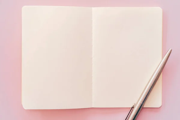 Cuaderno y pluma sobre fondo de textura rosa . —  Fotos de Stock