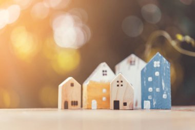 Ahşap masadaki küçük ev modeli, doğa yeşil bokeh soyut arka plan. Aile hayatı ve iş yeri konsepti.