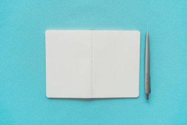 Mavi doku arkaplanı üzerine not defteri ve kalem.