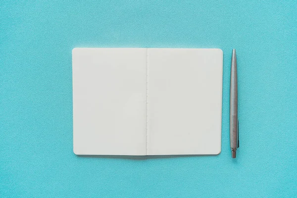 Cuaderno y pluma sobre fondo de textura azul . —  Fotos de Stock