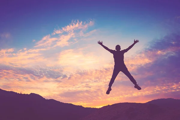 Счастливый человек прыгает на вершине горы с закатом неба абстрактный фон . — стоковое фото