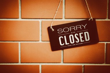 Close sign hanging on red stone wall texture background.