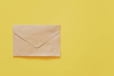 Brown paper envelope on yellow pastel abstract background. 