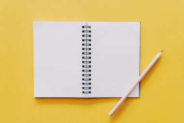 Notebook and pencil on yellow texture background.