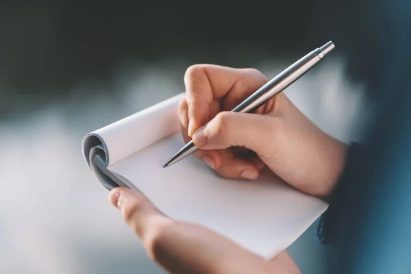 Vrouw hand vasthouden notebook en pen op outdoor park. — Stockfoto