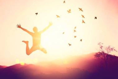 Siluet adam zıplıyor ve kuşlar gün batımında gökyüzünde uçuyor ve soyut arkaplan dokusunu bulutlandırıyor. İyi hissetme özgürlüğü ve seyahat macerası konseptini kopyala. Klasik ton filtre efekti renk biçimi.