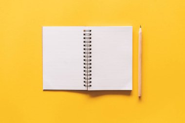 Notebook and pencil on yellow texture background.