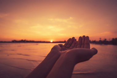 Kadın, tropik günbatımı arka planında elini kaldırıyor. Klasik ton rengi.