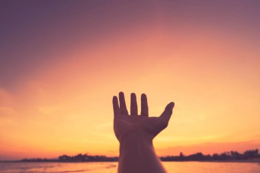 Adam tropikal günbatımı arka planında elini kaldırdı. Klasik ton rengi.